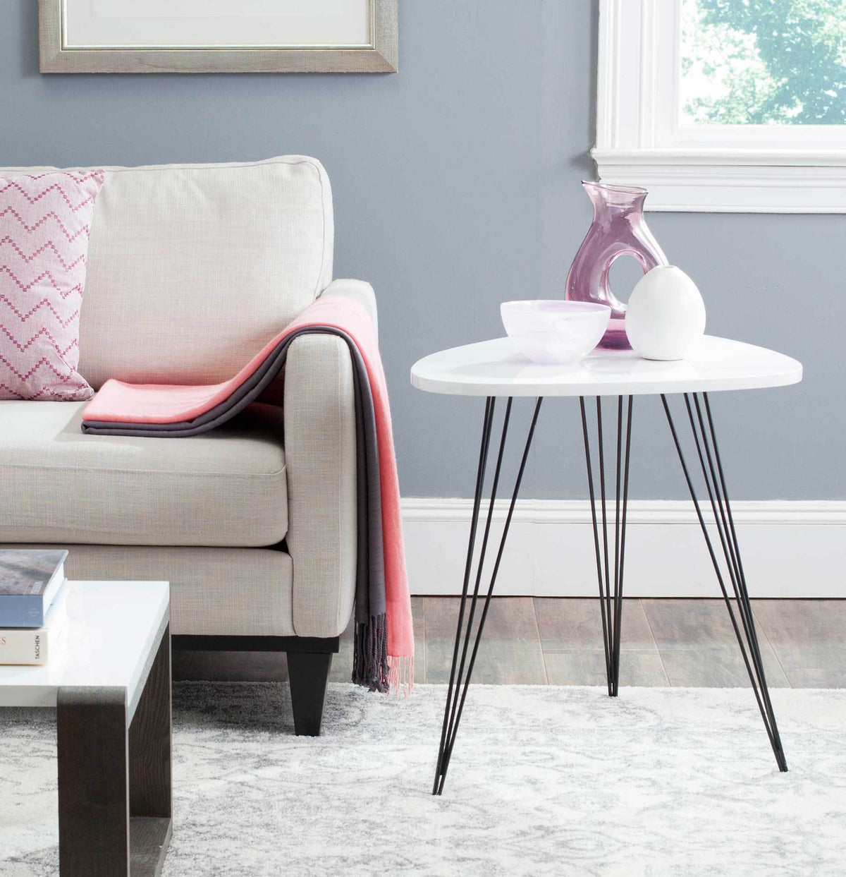 An airy white end table with slender black legs adds contrast beside a sofa.