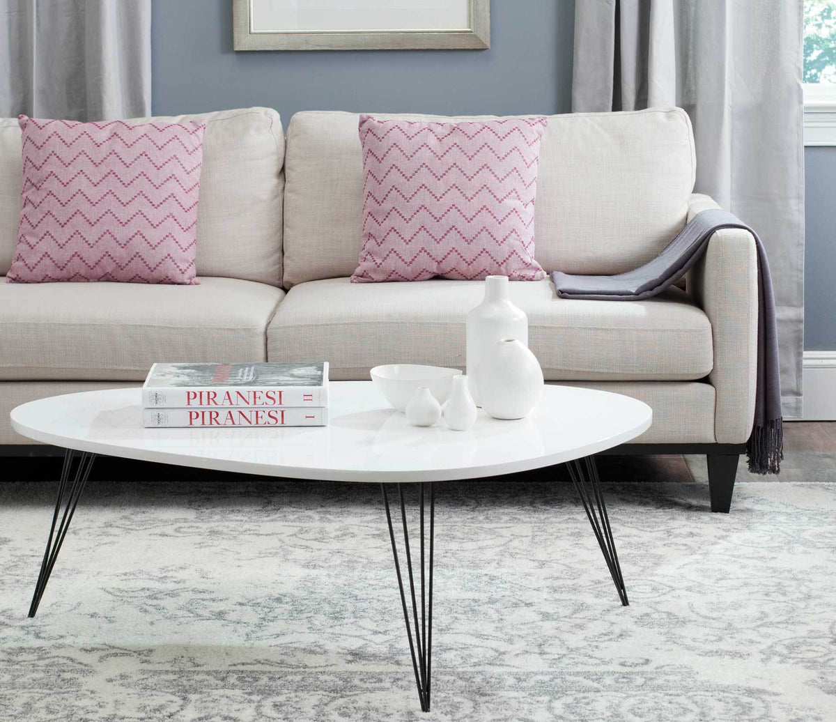 Sculptural white coffee table with a low, curved profile and slender black hairpin legs