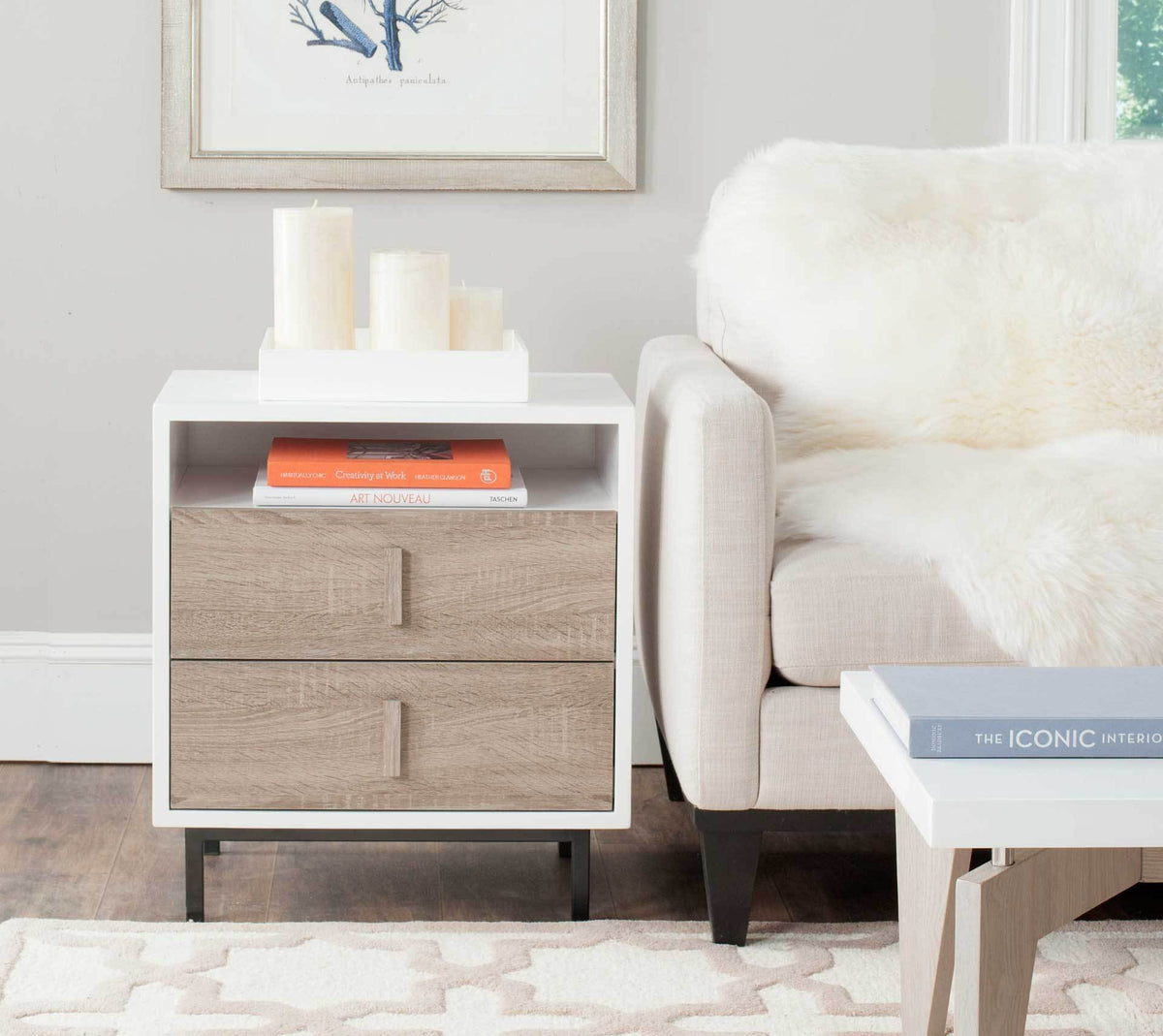 A white and oak-finished cabinet keeps books handy beside the sofa, with room on top for decor.