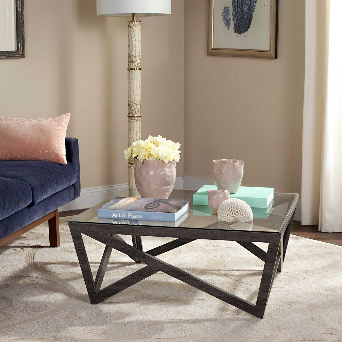 A glass tabletop and dark gray geometric base add airy, sculptural style to a living room.