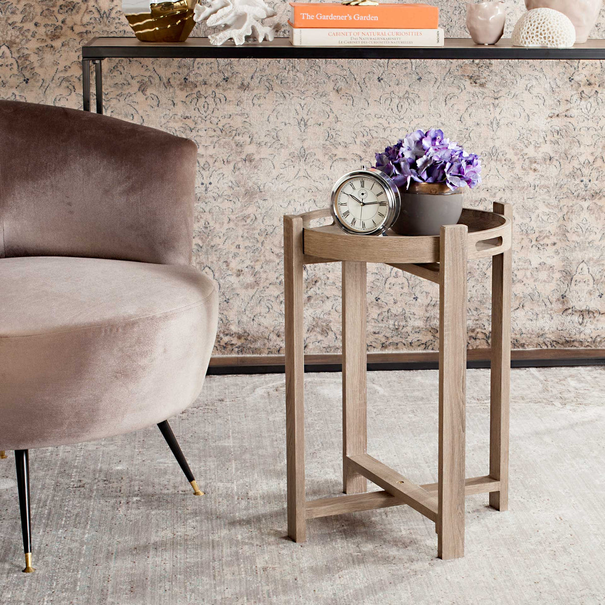 Rustic tray-top side table keeps a clock and flowers within reach beside an upholstered chair