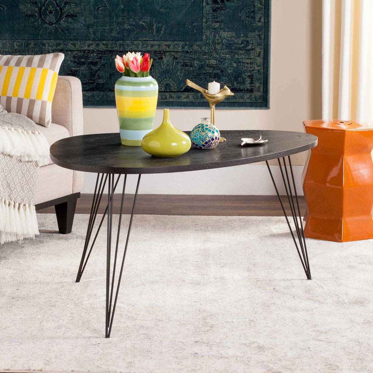 Black coffee table adds graphic contrast and an airy metal base to a bright living space.