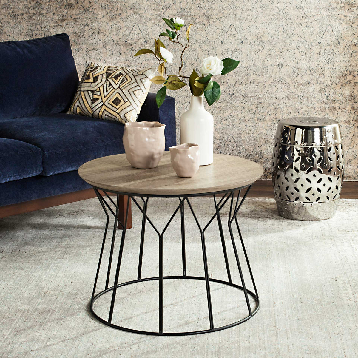 A round wood-look top and airy iron base bring midcentury character beside a sofa