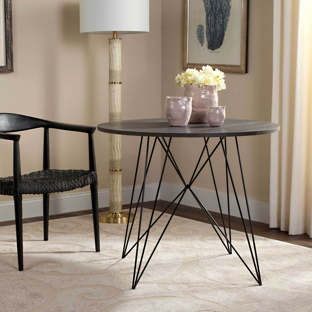 A dark gray round dining table brings a sculptural black iron base to the dining space.
