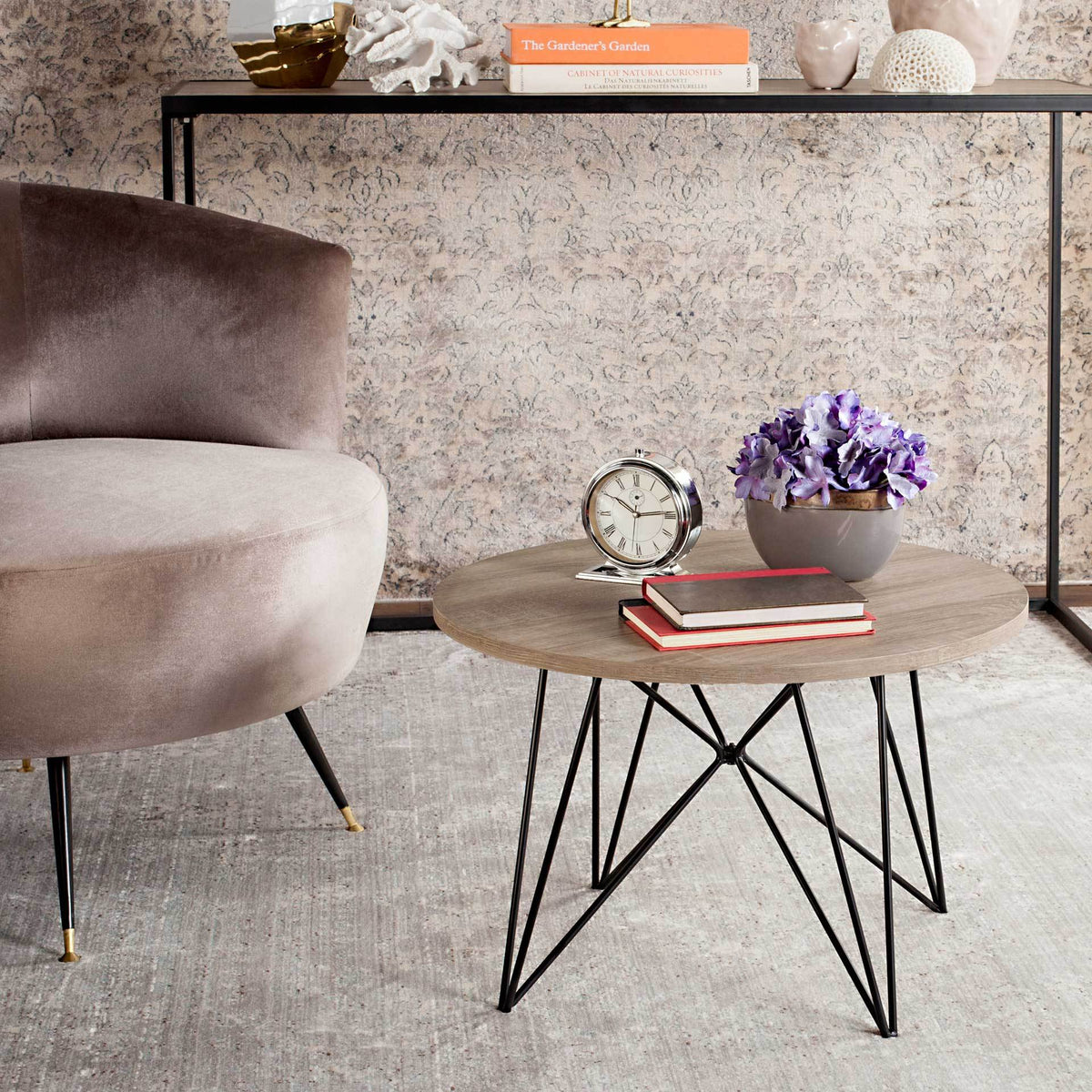 A warm wood-look top and intersecting black iron legs complement a plush seating area.