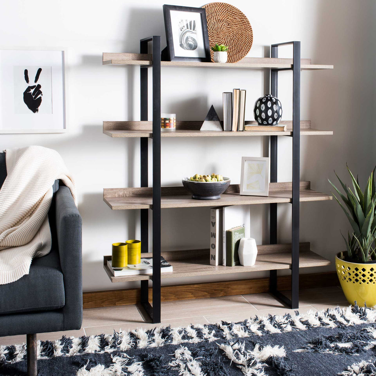 Four open shelves hold books and decorative accents in a warm wood-and-black metal design.