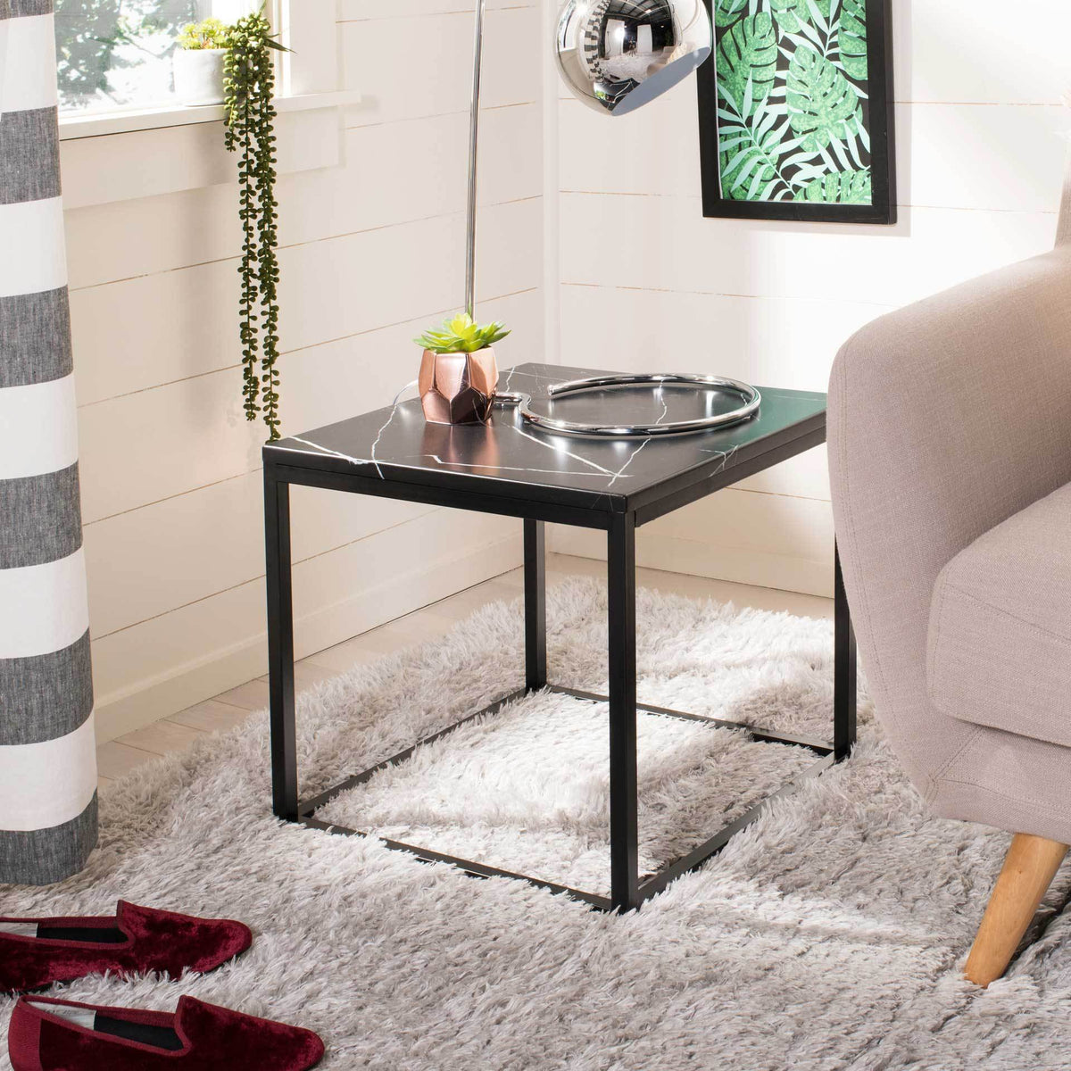 A veined black tabletop and airy metal frame add sleek style beside a sofa
