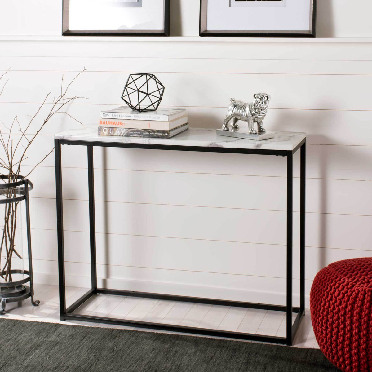 White marble-look console table displays books and sculptural decor against a paneled wall