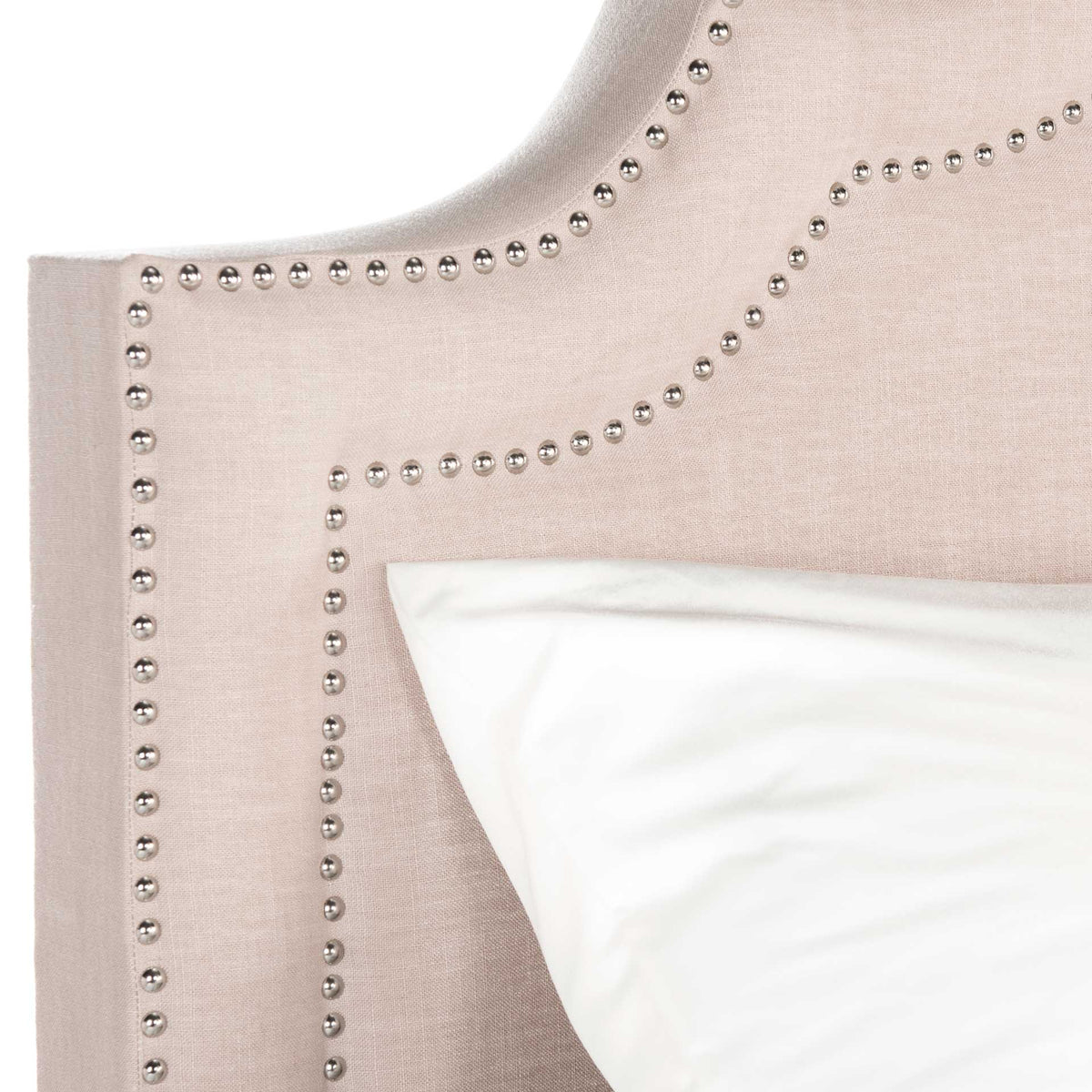 Silver nailheads outline the curves of a soft light beige linen headboard