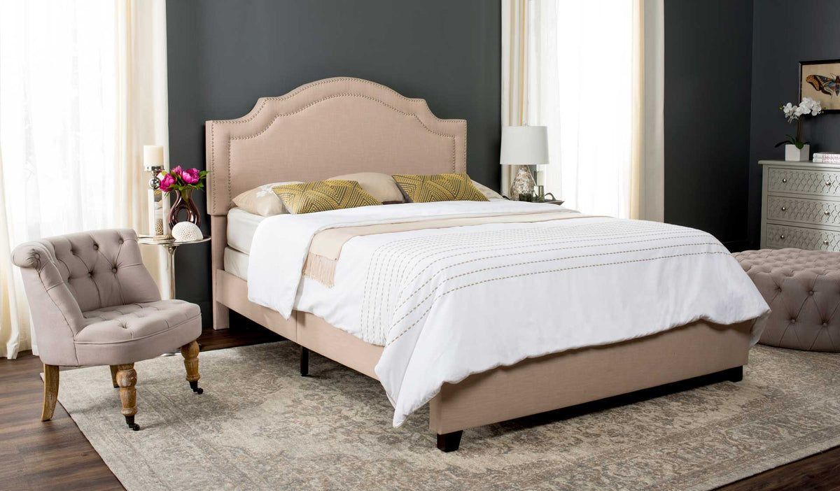 Light beige bed with a graceful scalloped headboard and dark feet grounds a cozy bedroom