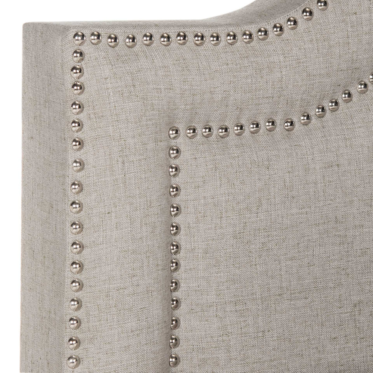 Silver nailheads trace double curves across a textured light gray linen headboard