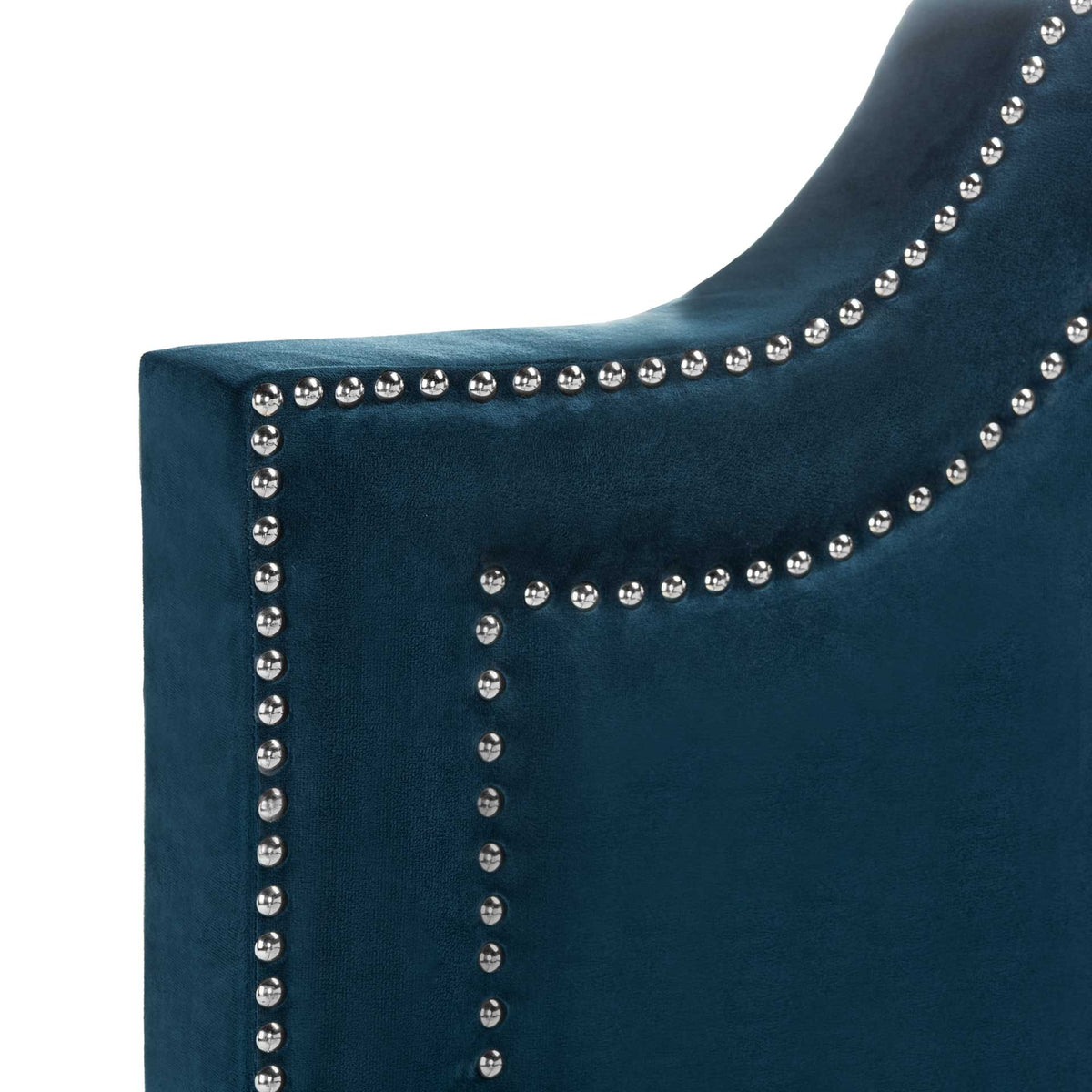 Silver nailheads trace the graceful curves of a plush navy velvet headboard