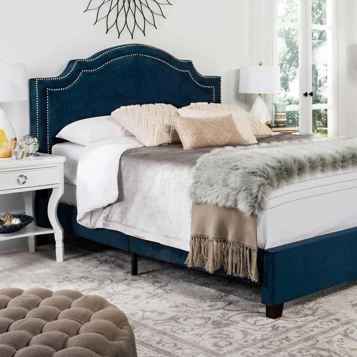 Rich navy velvet and silver nailheads dress a scalloped headboard above the upholstered rails