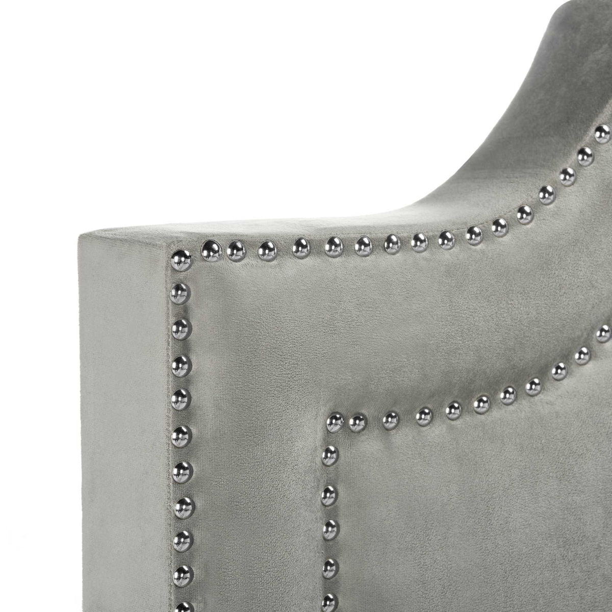 Shining silver nailheads follow the curved edge of a soft gray velvet headboard