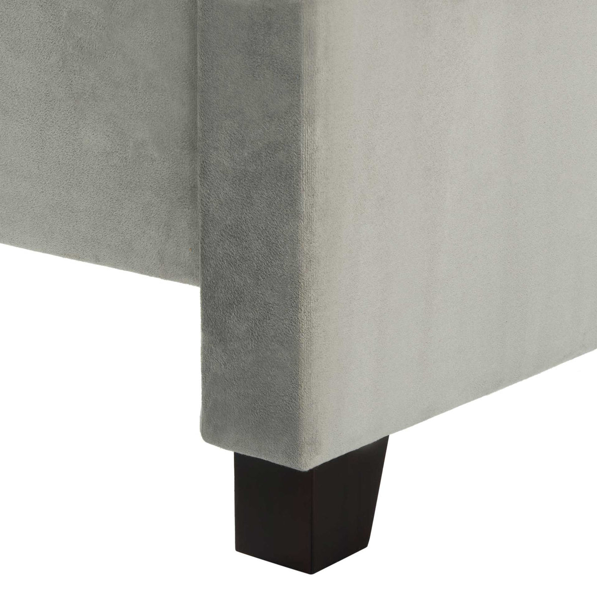 Dark wood block foot supports a soft gray velvet-wrapped bed frame