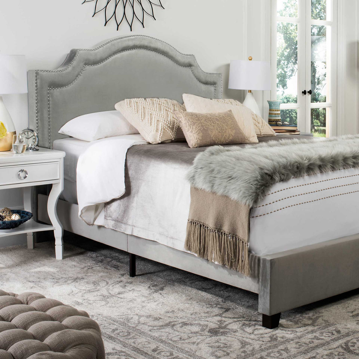 Plush gray velvet and silver nailheads accent the sculpted headboard above the bed frame