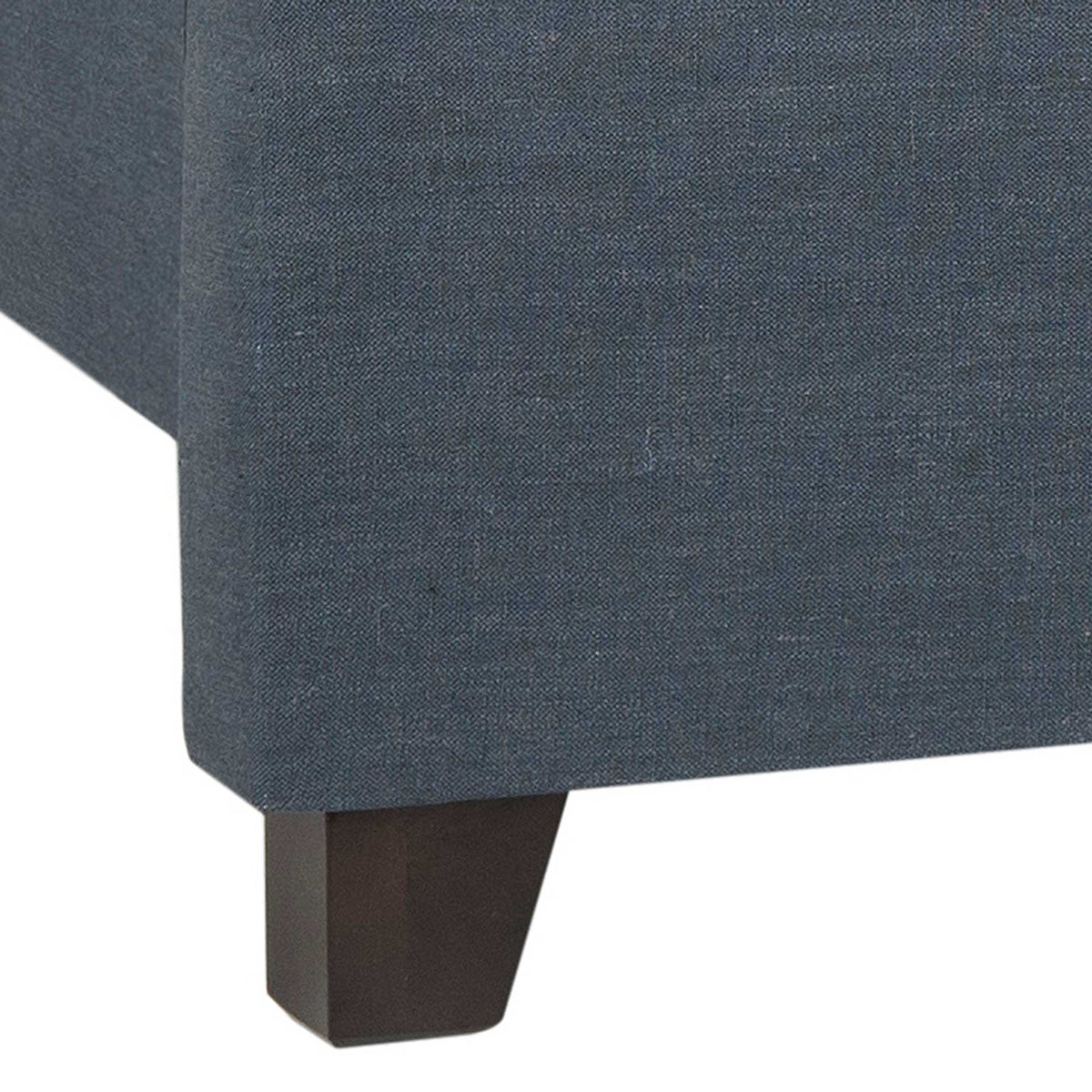 A dark espresso-finished foot lifts the navy upholstered bed frame above the floor.