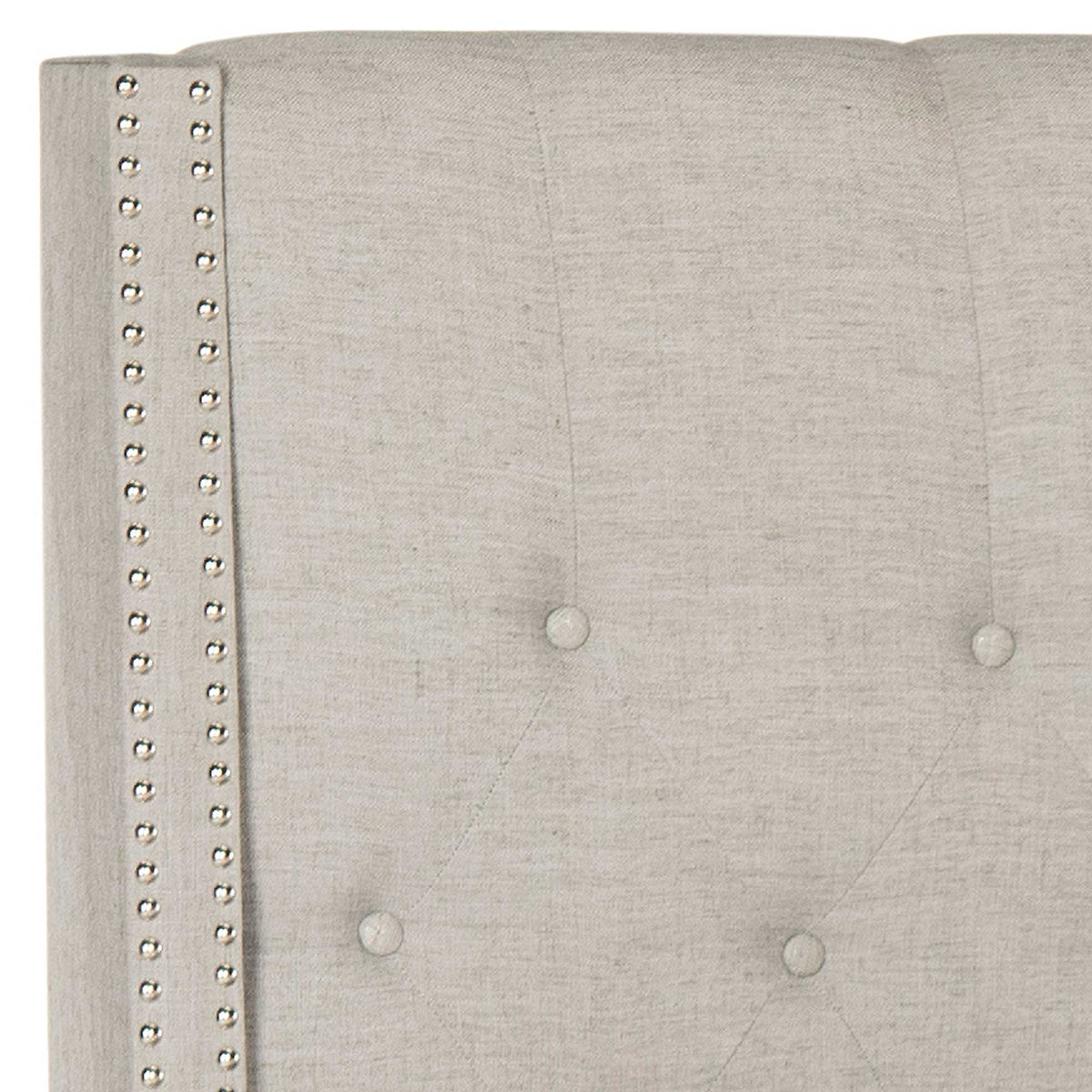 Fabric-covered buttons and two rows of silver nailheads accent the light gray linen headboard.