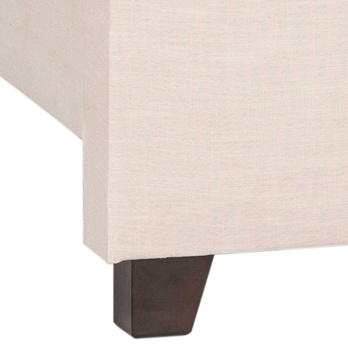 A tapered espresso-finished wood foot contrasts with the bed's pale beige linen upholstery.
