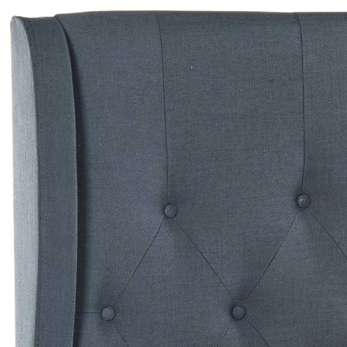 Covered buttons and curved wings add tailored texture to the deep navy linen headboard.