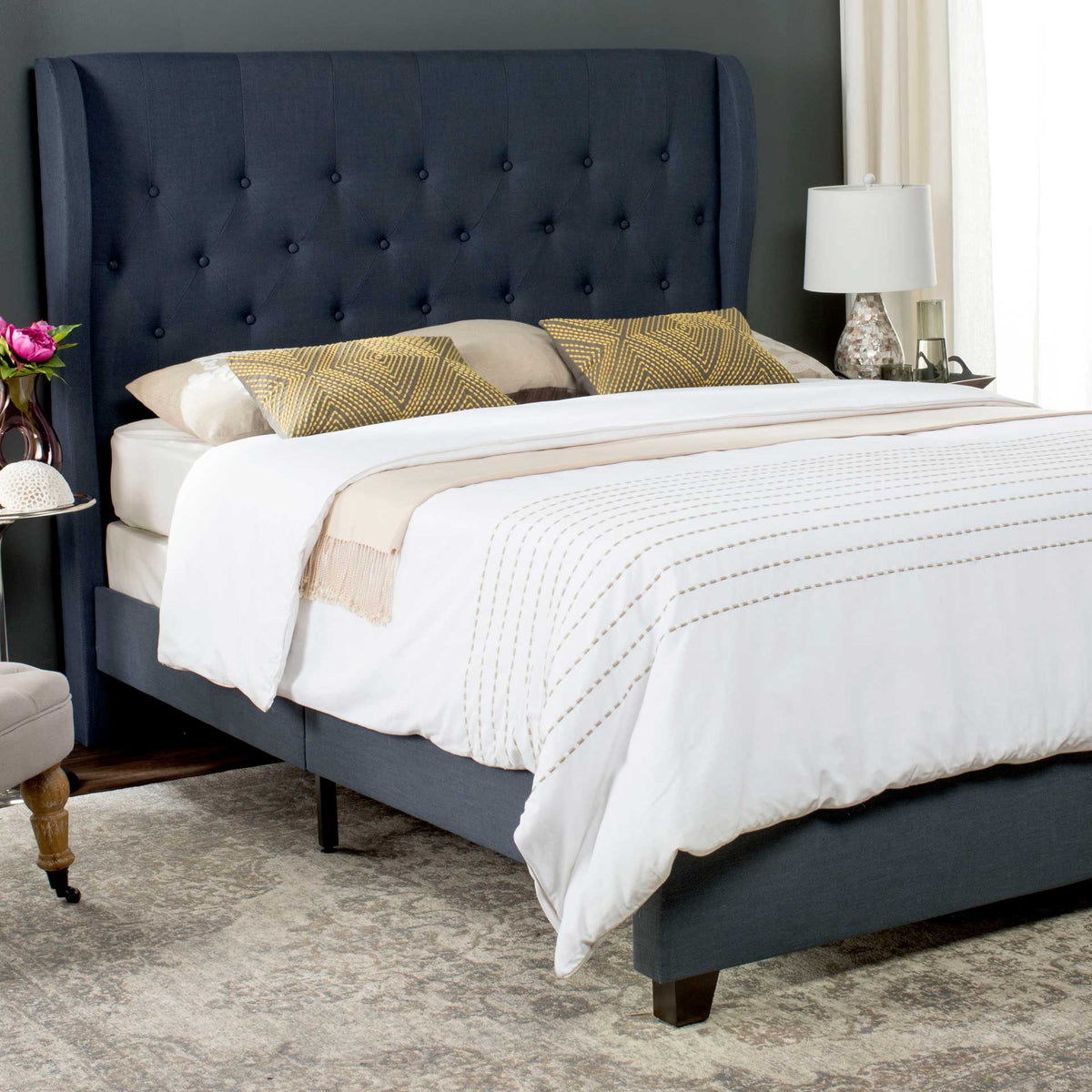 Button tufting adds texture to the tall navy headboard, while matching linen covers the bed frame.