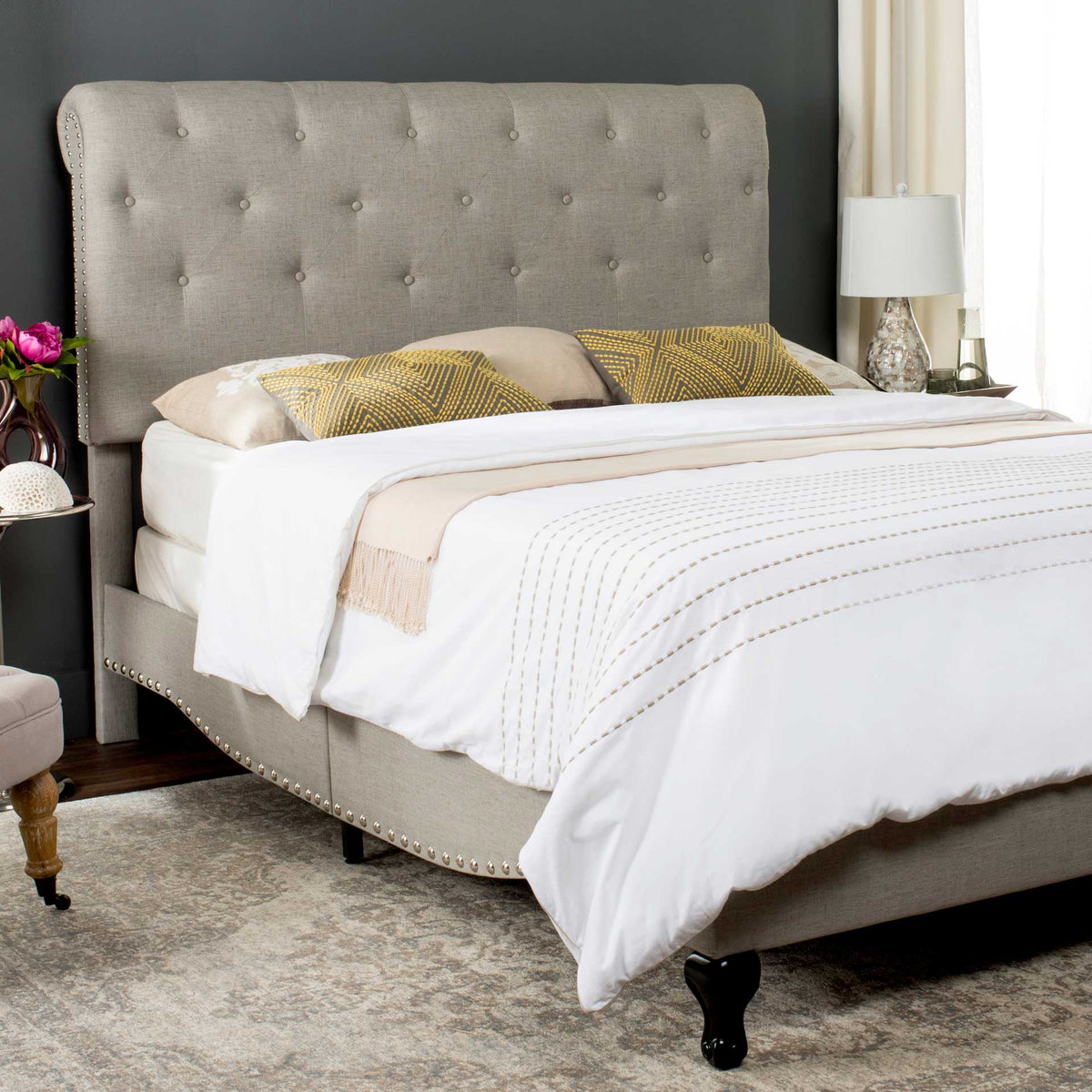 Curved upholstered side rails and silver nailheads complement a tall, button-tufted linen headboard