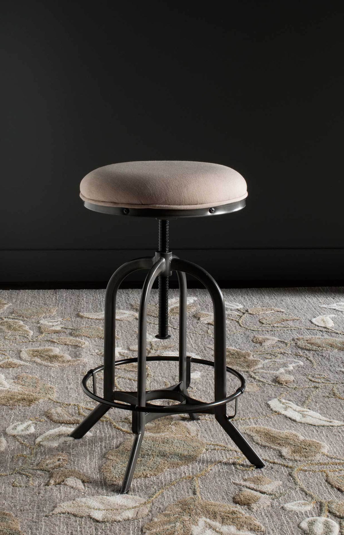 Beige upholstery softens the raised iron stool and its wraparound footrest.