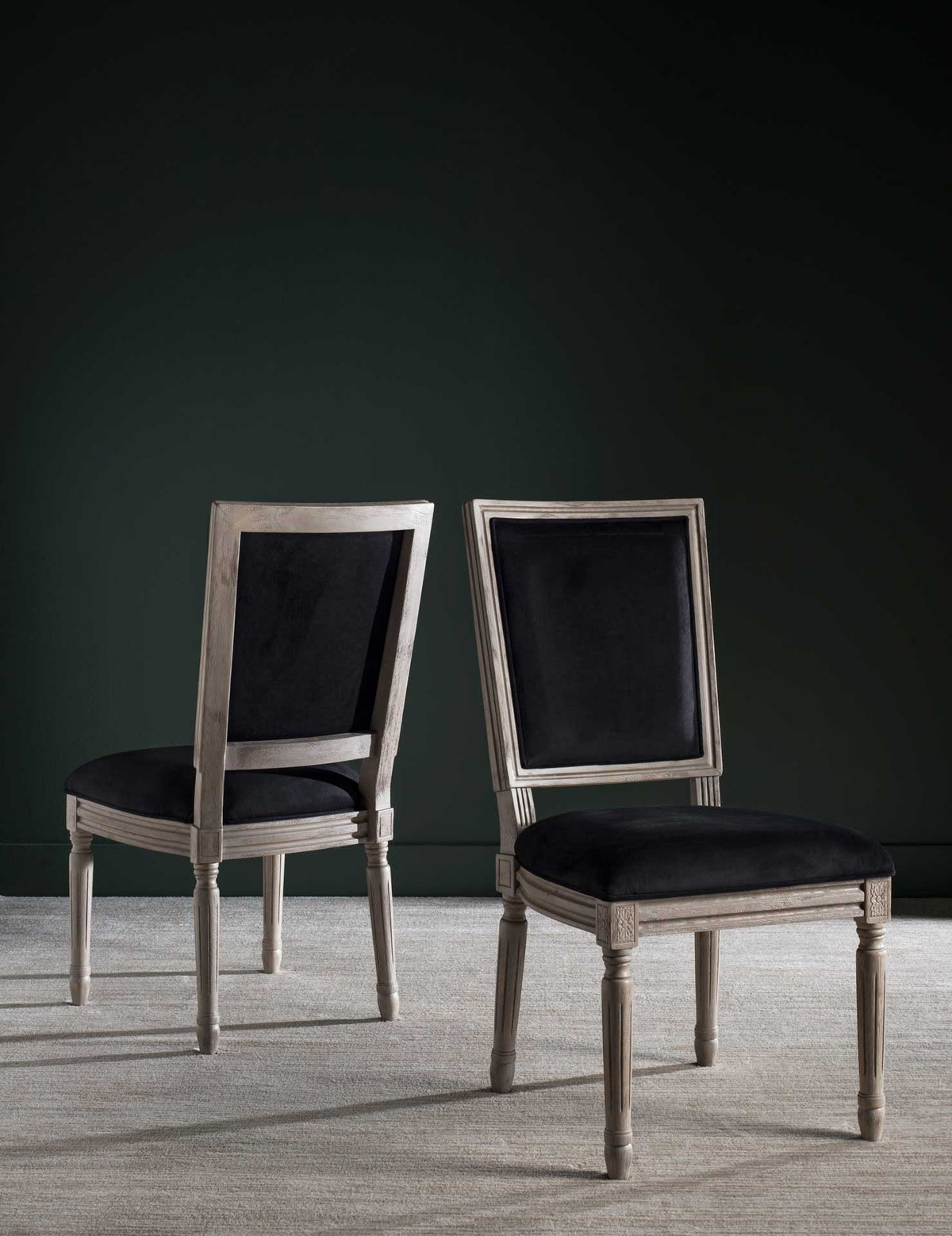Two black velvet dining chairs balance dramatic upholstery with rustic gray carved wood.