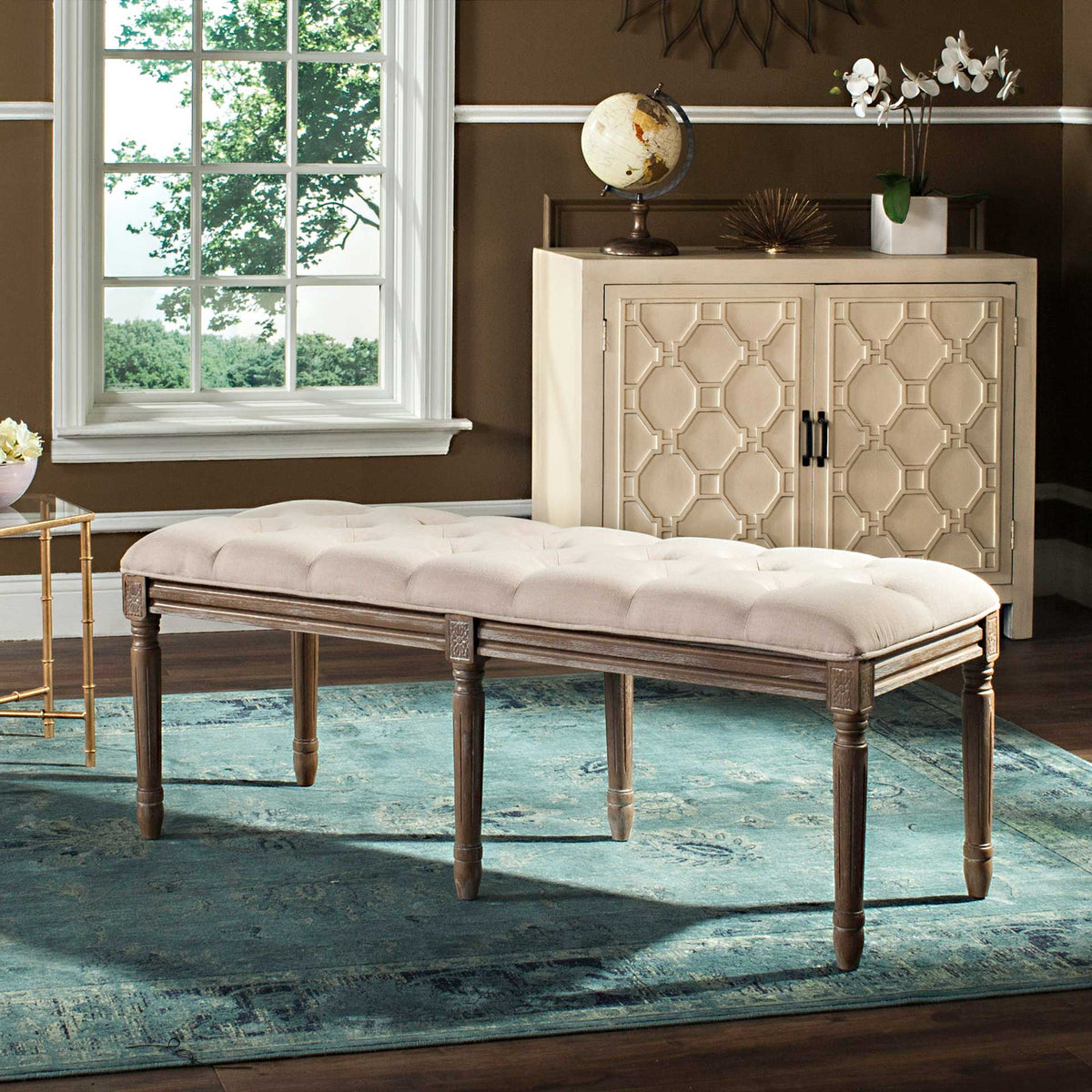 Beige tufted cushioning and distressed wood legs lend French-inspired charm to an upholstered bench