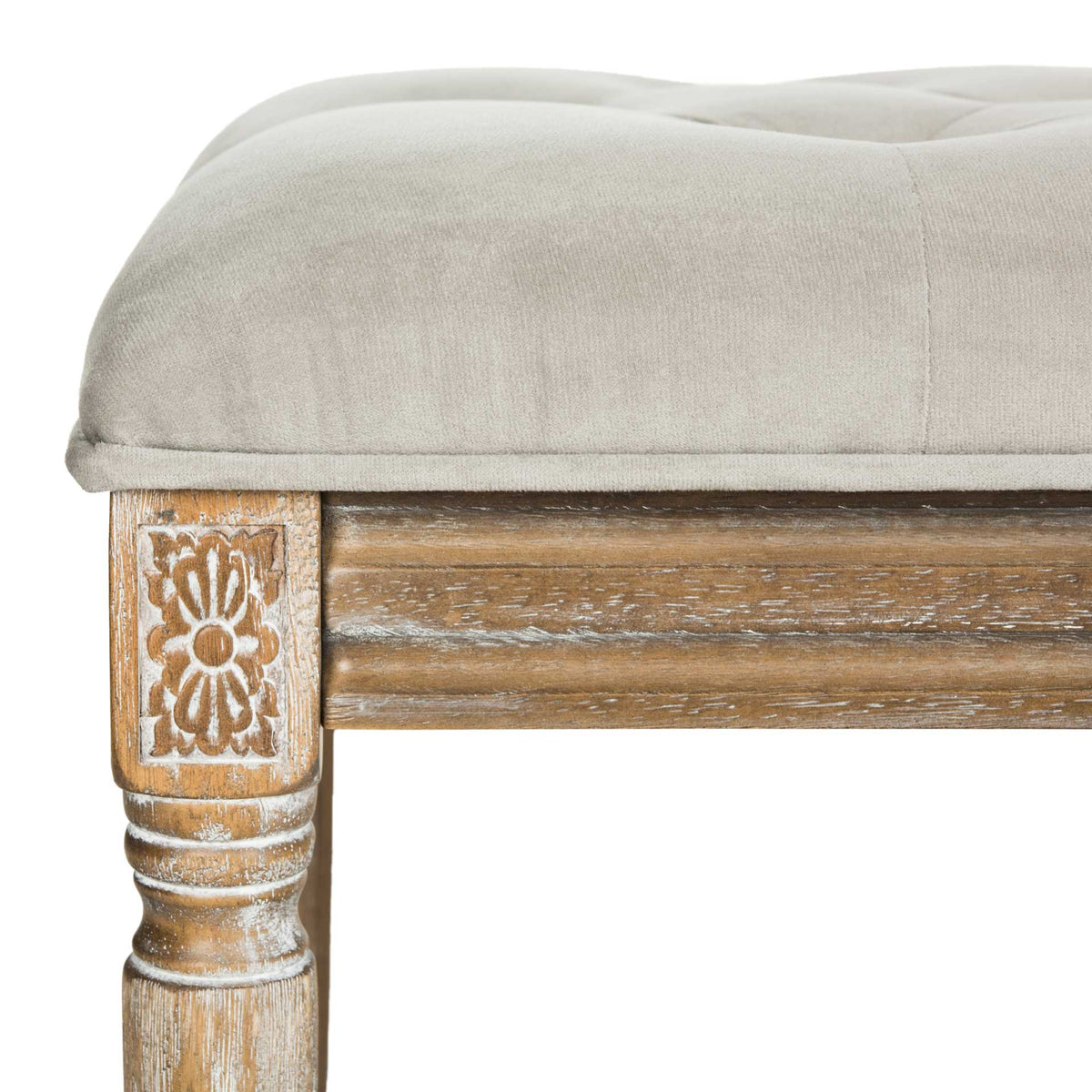 Gray velvet upholstery meets an ornate floral-carved corner and distressed wood trim