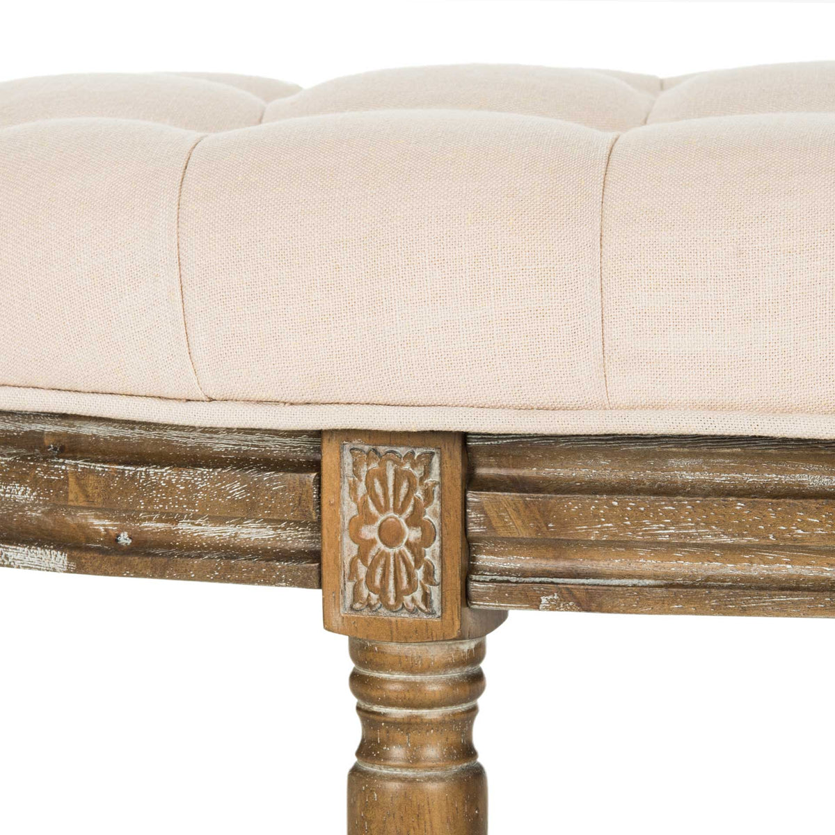 A floral carving and distressed wood grain accent the button-tufted beige linen cushion