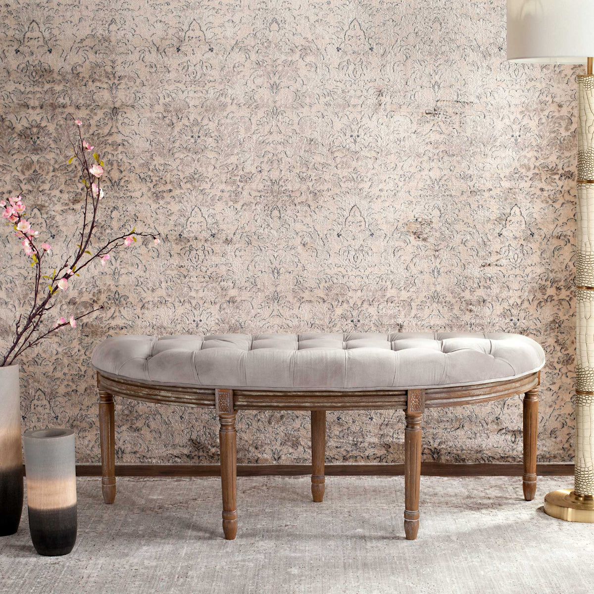 Slender turned legs frame the gracefully curved apron beneath a gray button-tufted seat