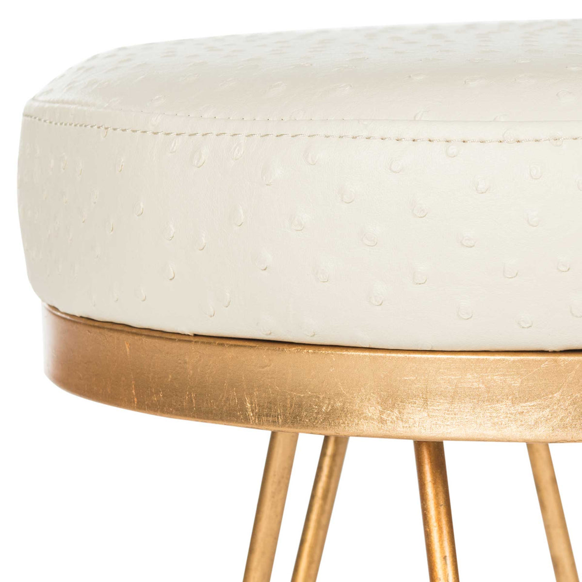 Embossed dots and neat stitching accent the cream seat above a gold-tone rim