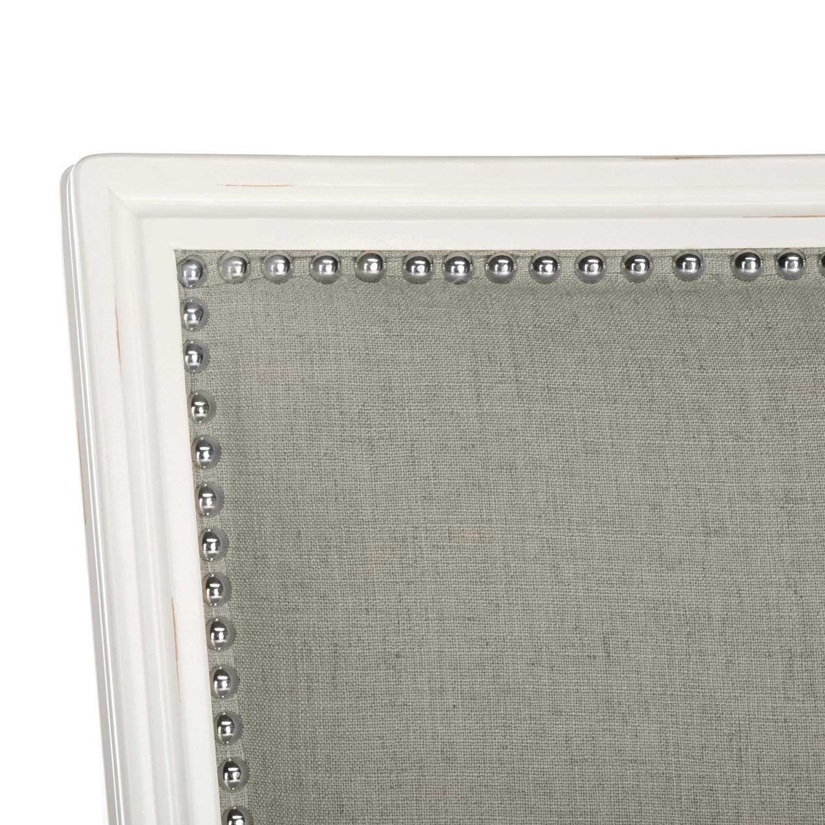 Shiny silver nailheads trace the gray linen back within its grooved white wood frame.