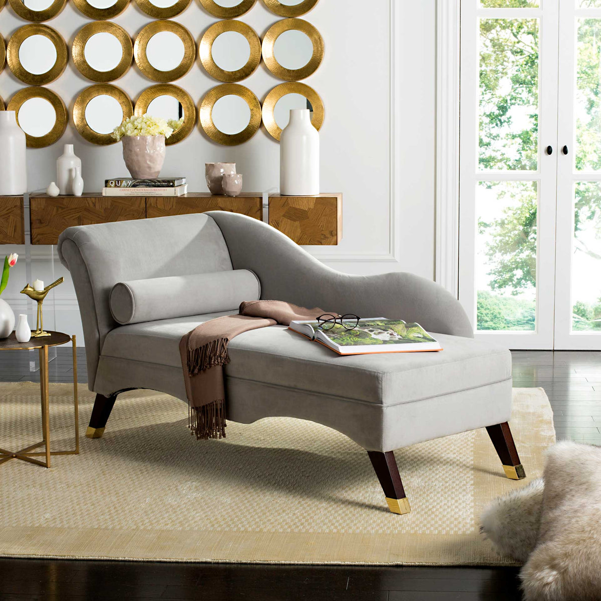 Gray velvet chaise offers a plush place to lounge with its sweeping back, bolster, and gold-capped legs