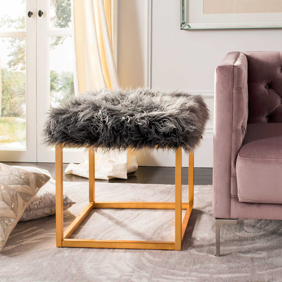 A plush gray faux sheepskin seat adds soft texture to a gleaming gold metal base.
