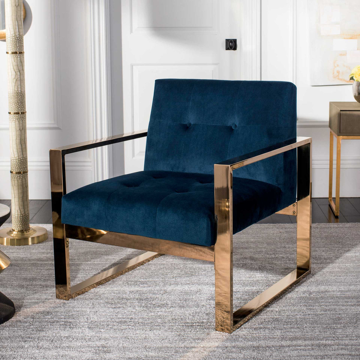 Navy velvet cushions and a polished brass-tone frame bring modern elegance to a living room