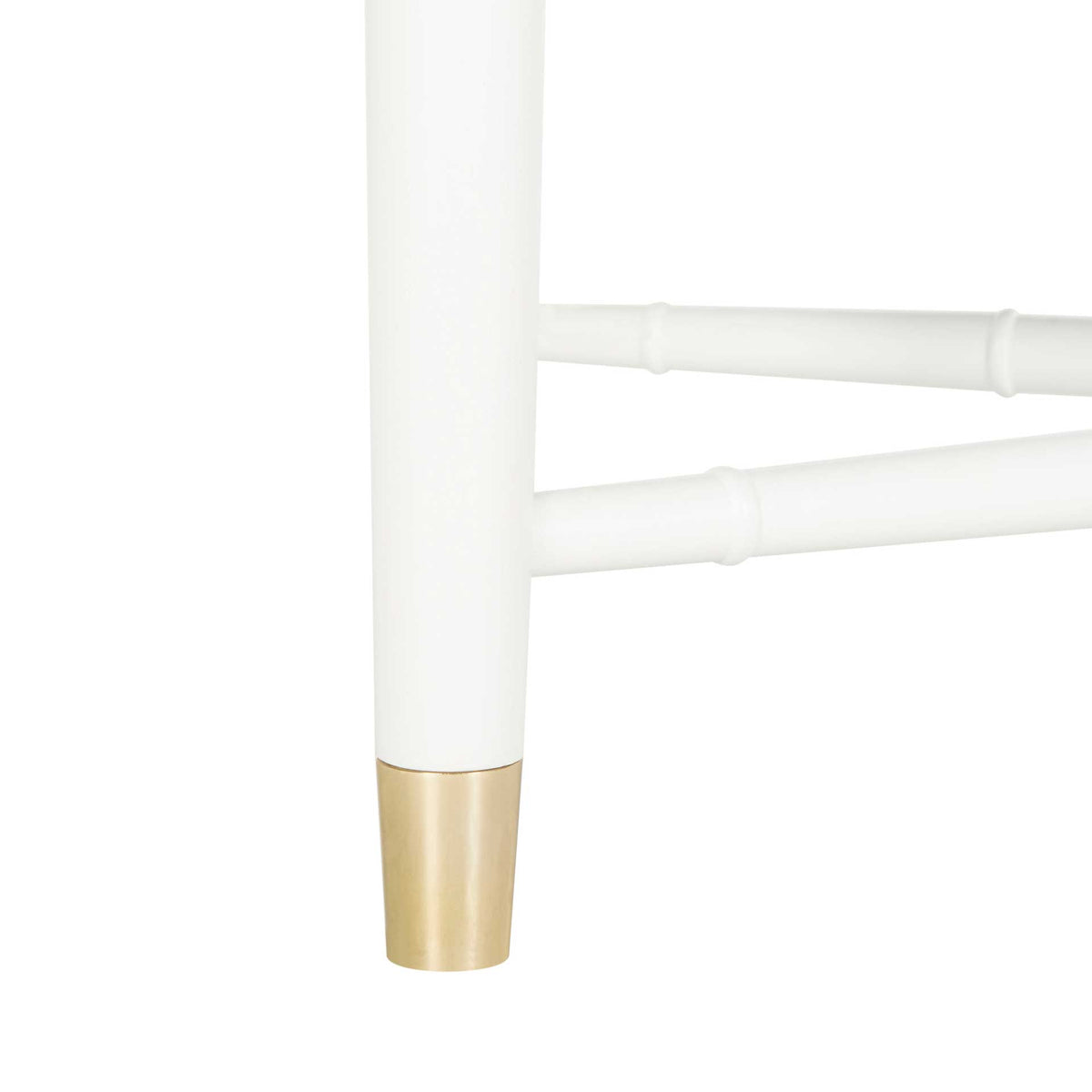 A white bamboo-style leg and crossed stretchers meet at a gleaming brass-capped foot