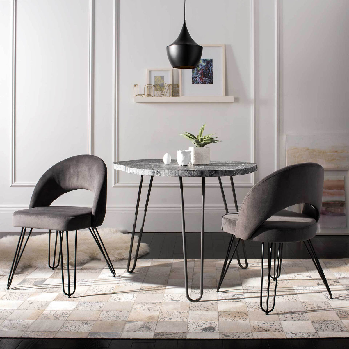 Two dark gray velvet chairs bring curved silhouettes and black hairpin legs to a dining nook