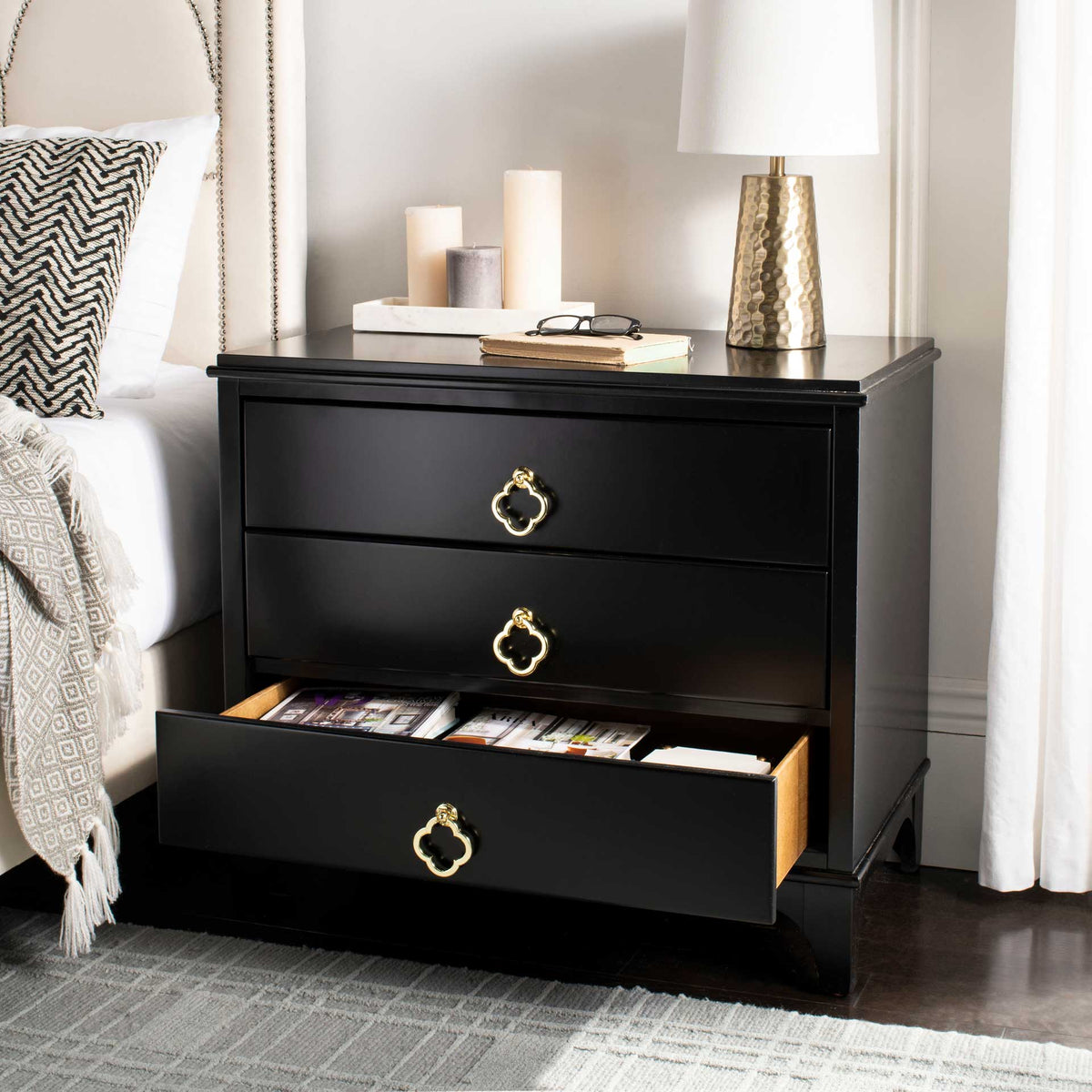 A wide lower drawer keeps magazines close at hand beneath two brass-accented black drawers