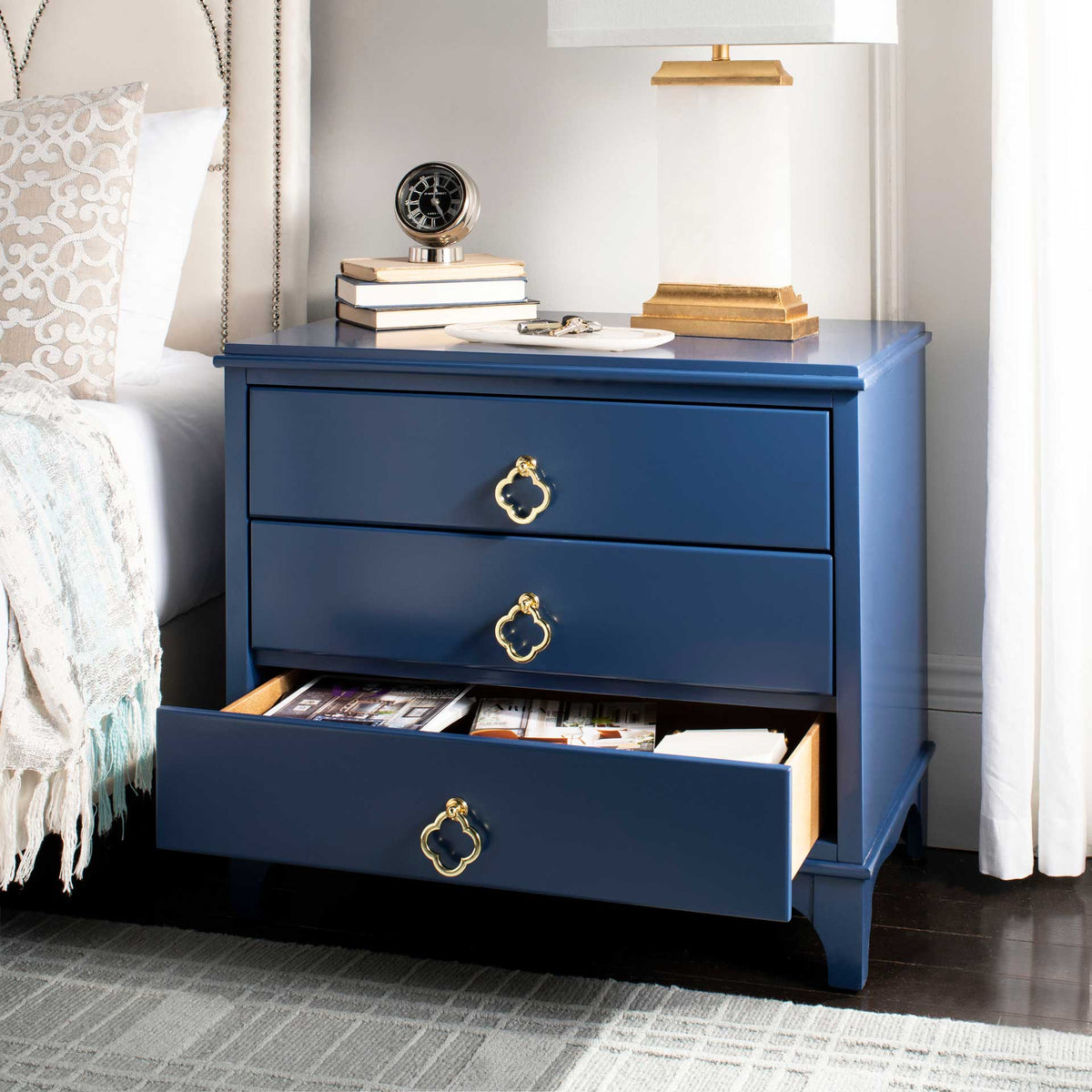 An open lower drawer keeps reading materials in reach beneath a spacious navy top