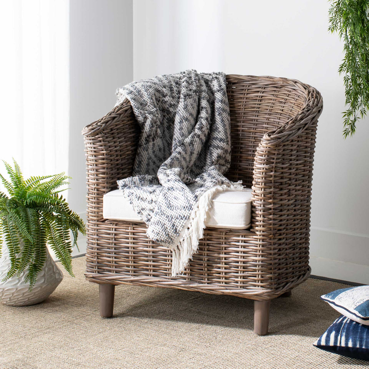 A natural woven rattan frame surrounds a white cushion with cozy texture and curved arms.