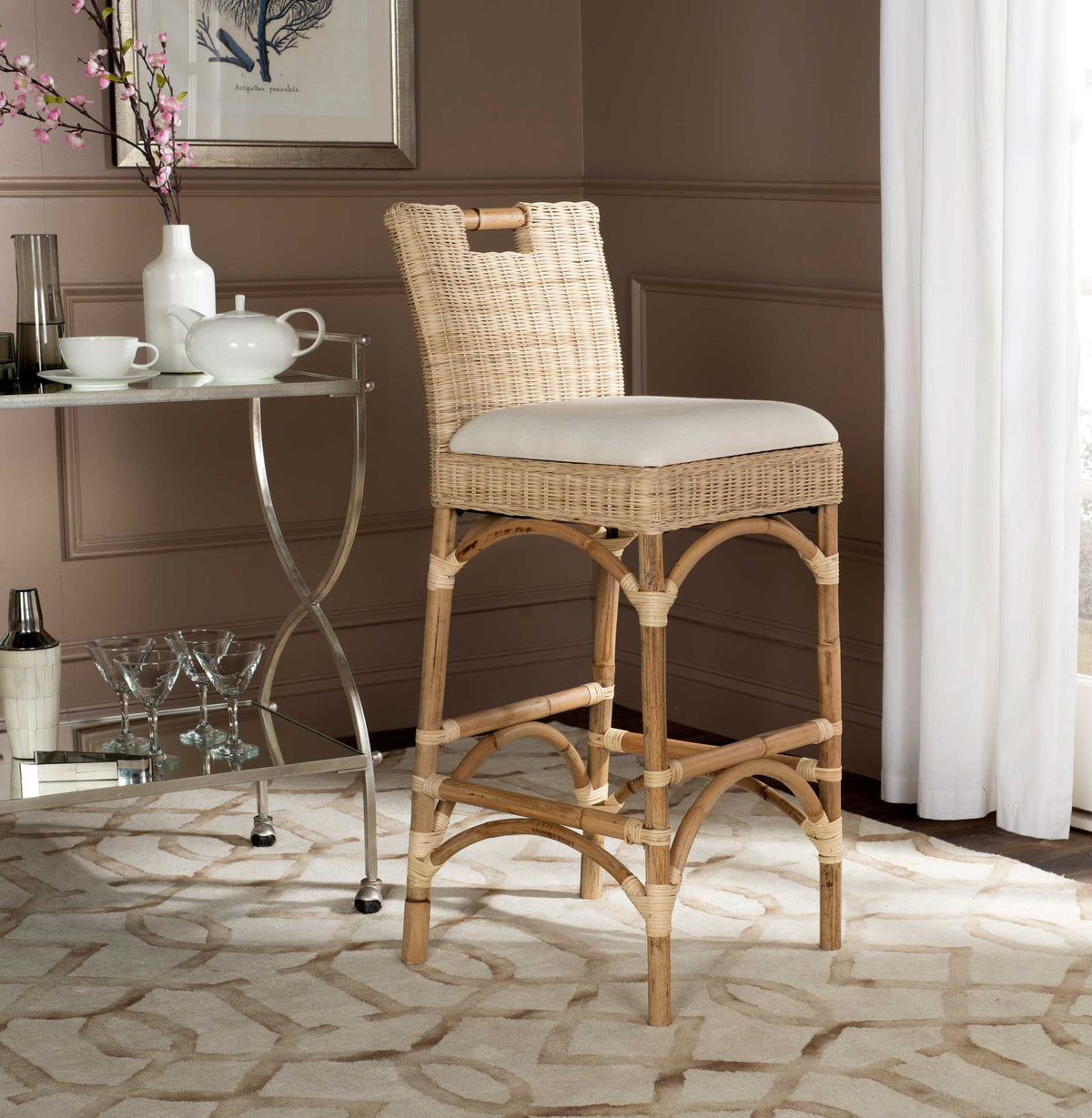 Pale woven rattan and an ivory cushion give this tall bar stool an airy look beside a glass-topped table.