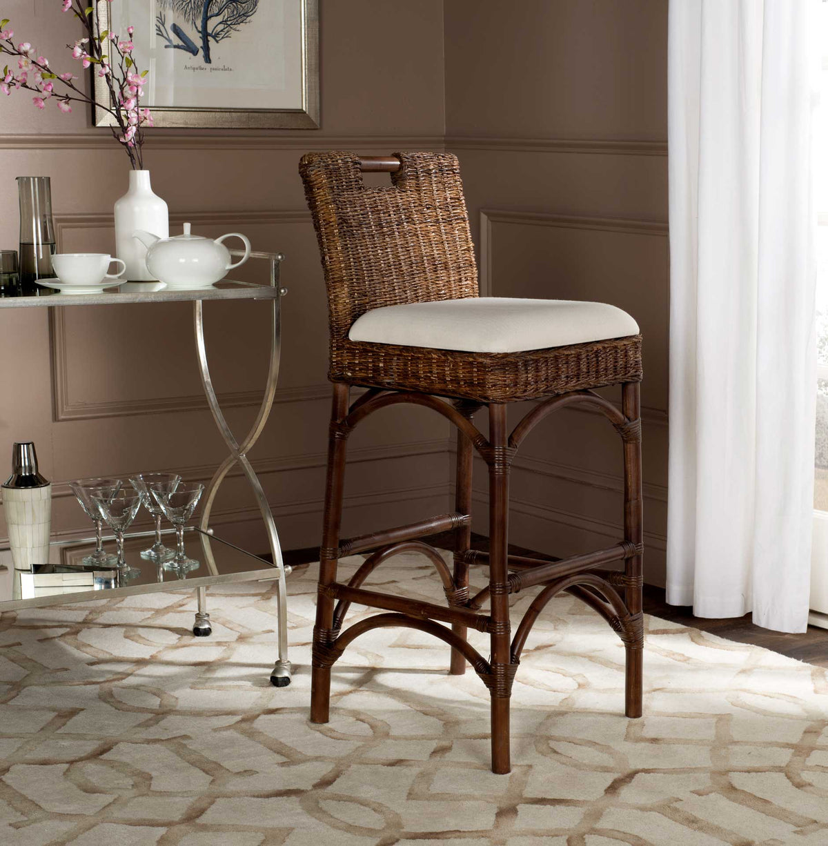 A brown woven rattan bar stool with an ivory seat and arched legs adds warm texture beside a table.