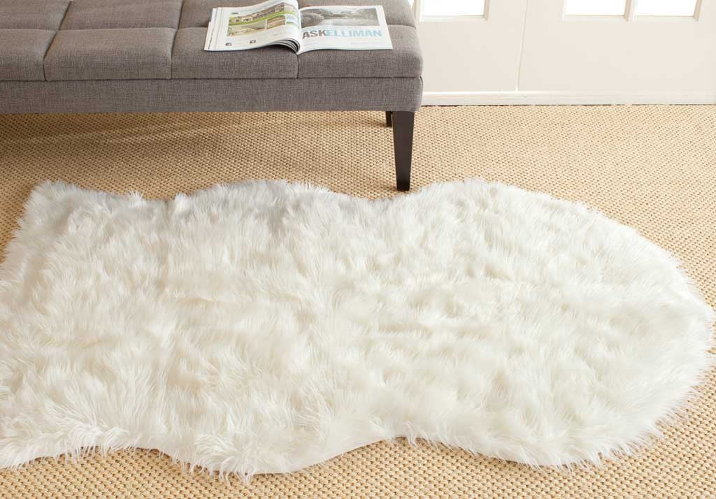 Fluffy ivory hide-shaped rug layers plush texture over a woven floor covering