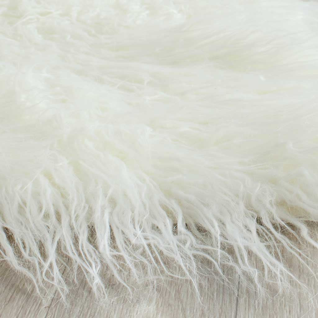 Long ivory faux-fur strands drape over the rug's edge in loose, feathery layers