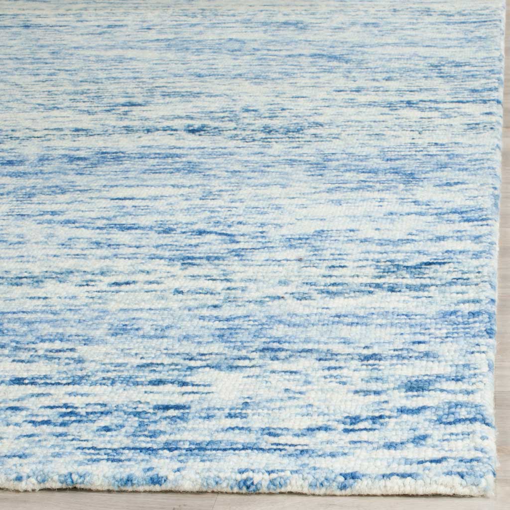 Subtle blue streaks flow across soft ivory wool toward a neatly finished edge