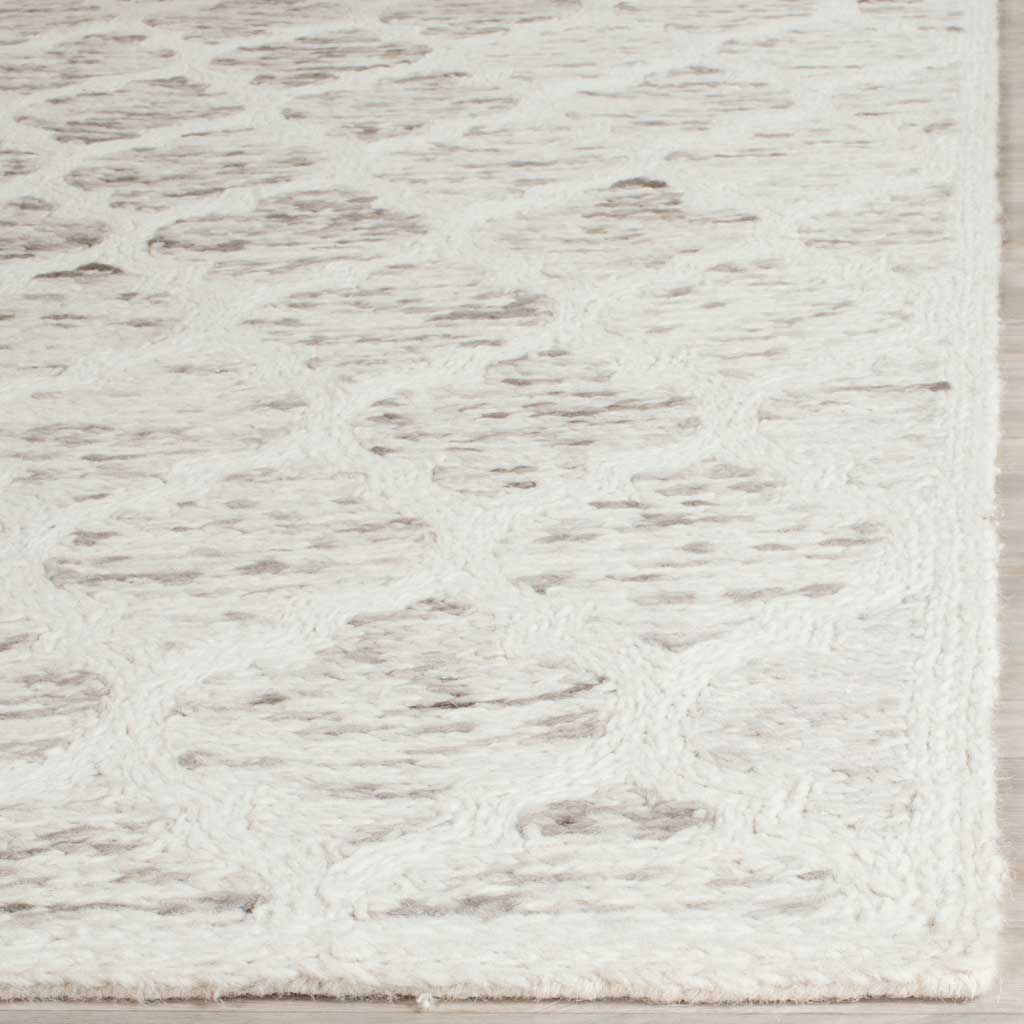 Mottled gray motifs peek through the ivory field, finished with a neatly bound wool edge