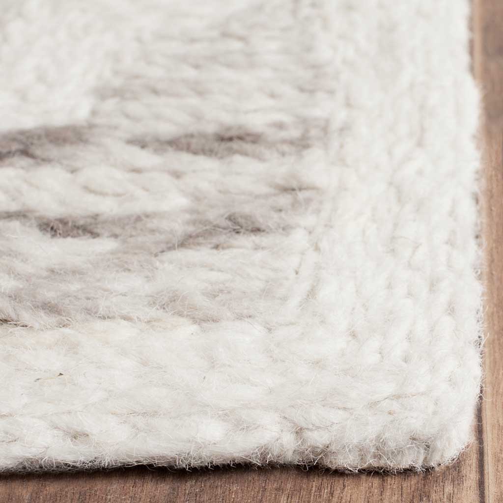 Ivory wool edging meets softly shaded gray motifs in a plush, hand-loomed texture
