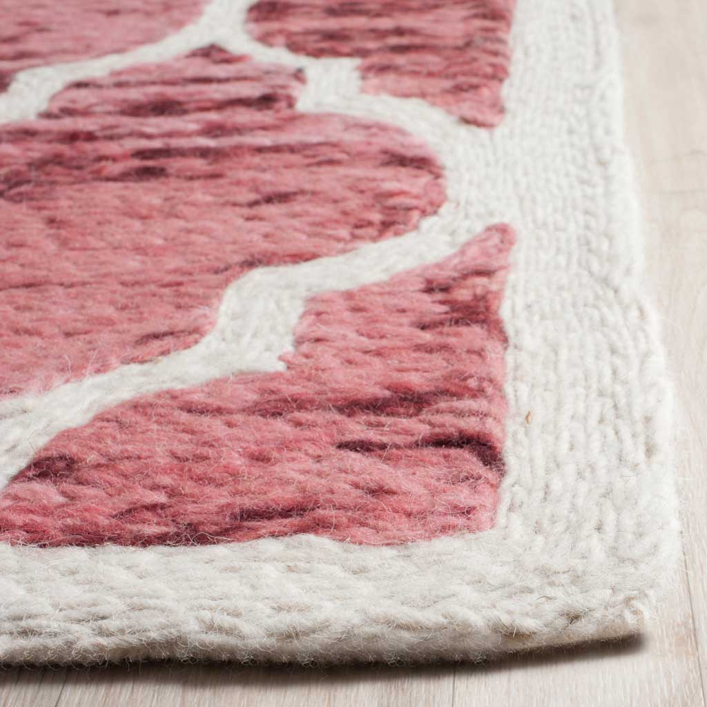 Ivory wool trim frames plush, striated red motifs for a refined finished edge